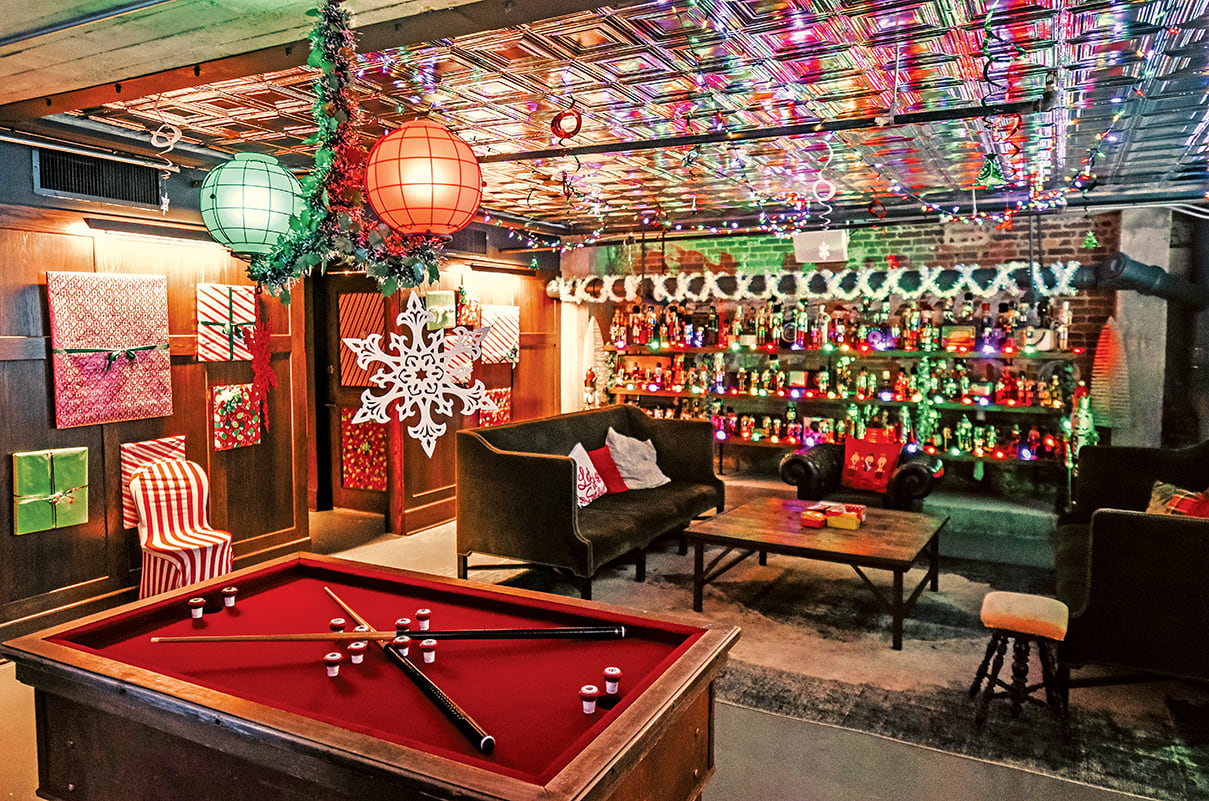 A festive basement bar with a pool table, Christmas decorations, and a wall of liquor bottles in Atlanta, Georgia.