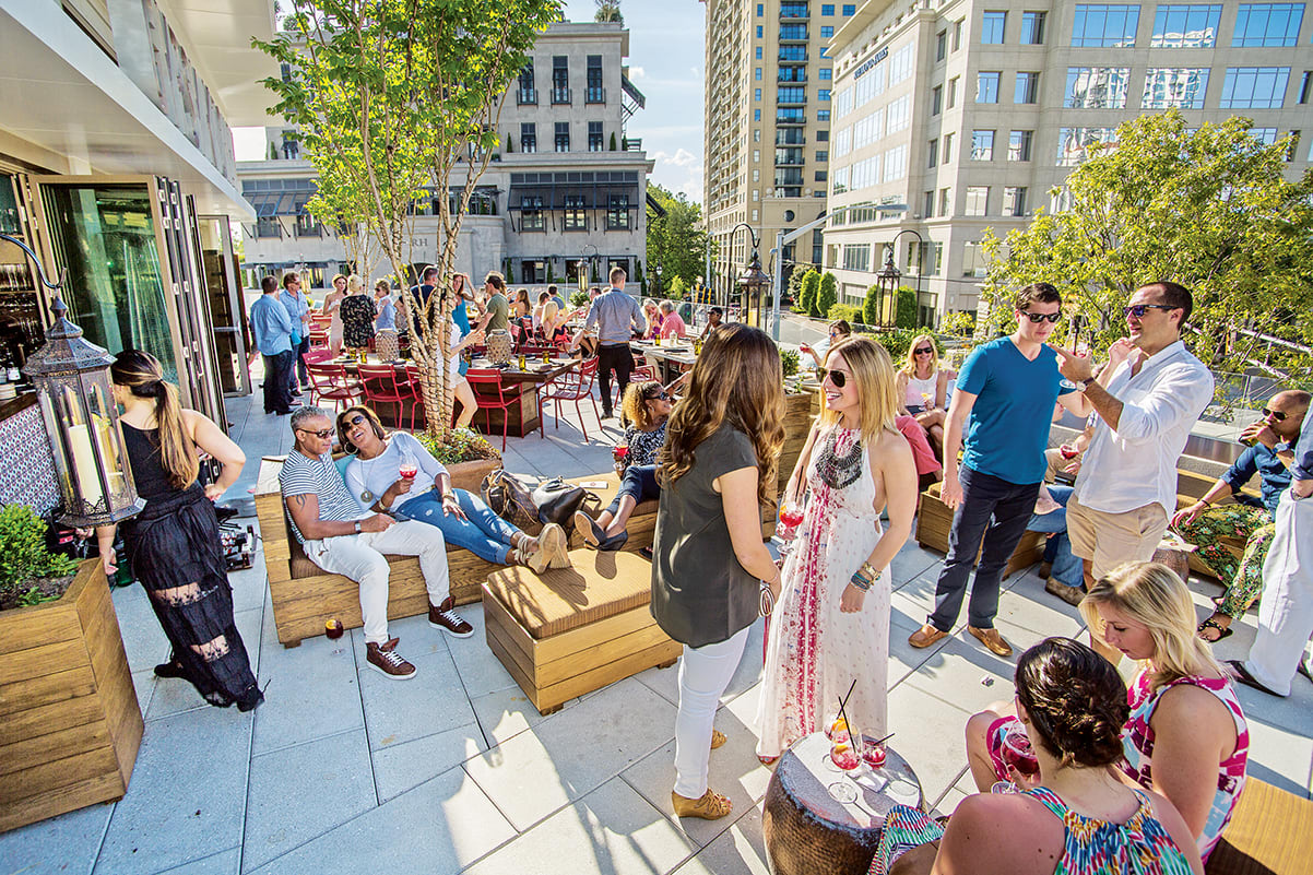 A lively rooftop party with people mingling, dining, and enjoying drinks in an urban setting in Atlanta, Georgia.