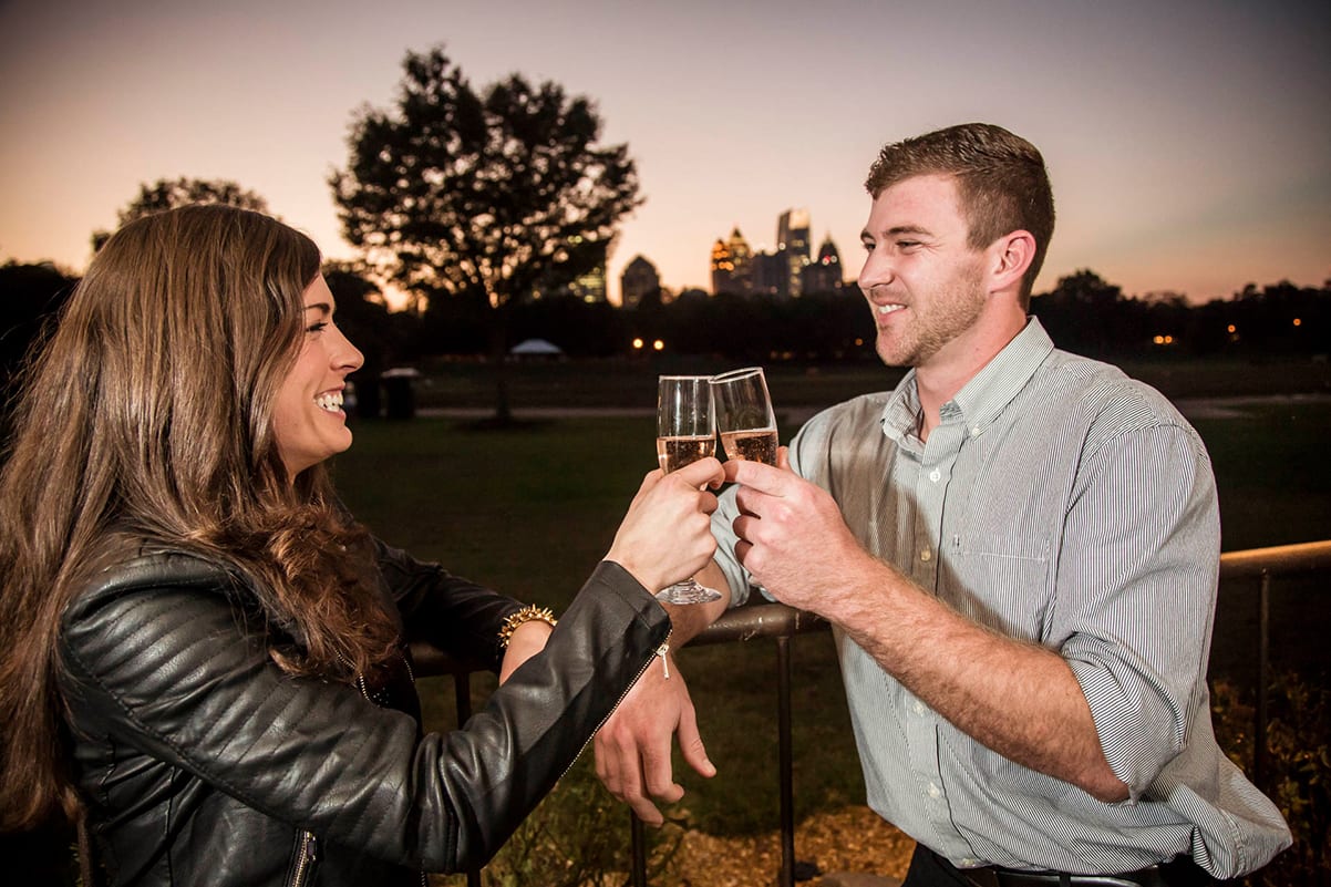 A couple toasts with champagne glasses at sunset in a park in Atlanta, Georgia.