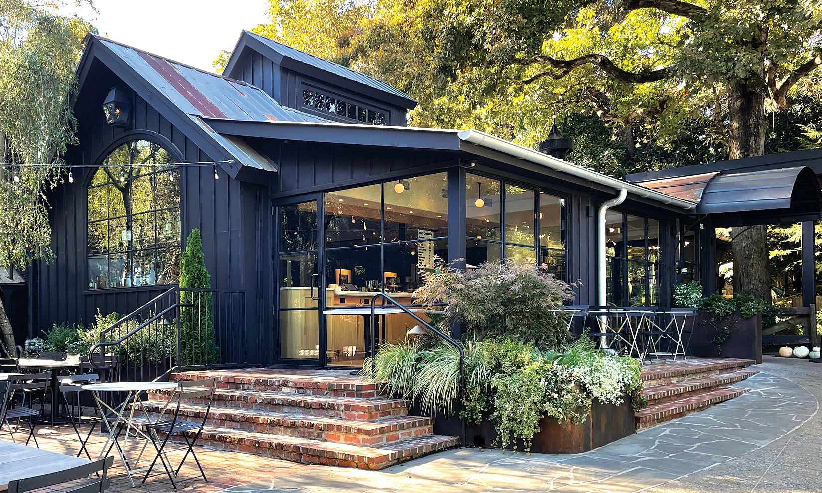 A modern black house with large windows and a brick patio surrounded by trees in Atlanta, Georgia.