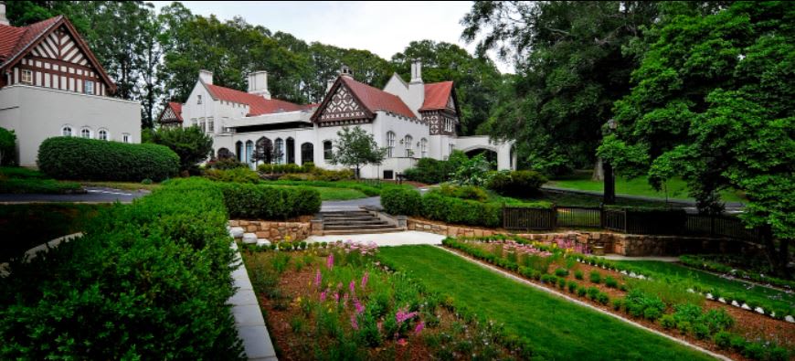 A picturesque garden with colorful flowers, manicured lawns, and a grand white house with red-tiled roofs in Atlanta, Georgia.