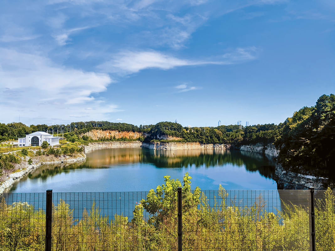 A serene lake nestled between rocky cliffs, surrounded by lush greenery and a distant city skyline in Atlanta, Georgia.