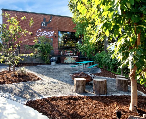 Outdoor patio with picnic tables, fire pit, and brick building with 'Garage' sign in Atlanta, Georgia.
