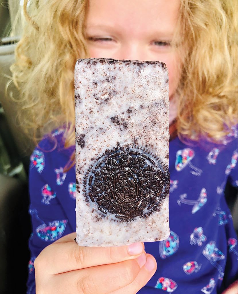 A young girl with blonde curls holds up an Oreo-flavored ice cream bar in Atlanta, Georgia.