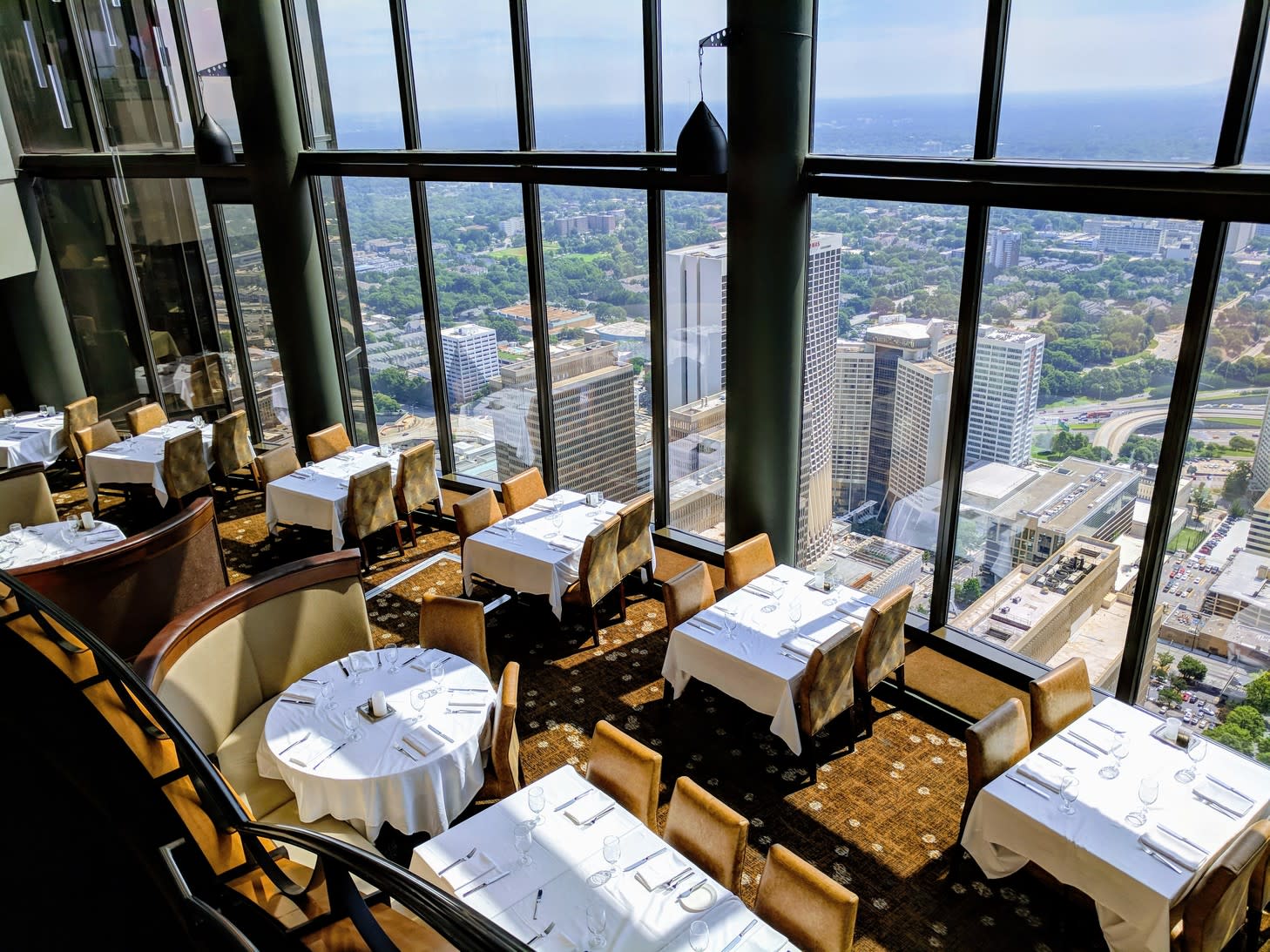 A modern restaurant with floor-to-ceiling windows overlooking a sprawling cityscape in Atlanta, Georgia.