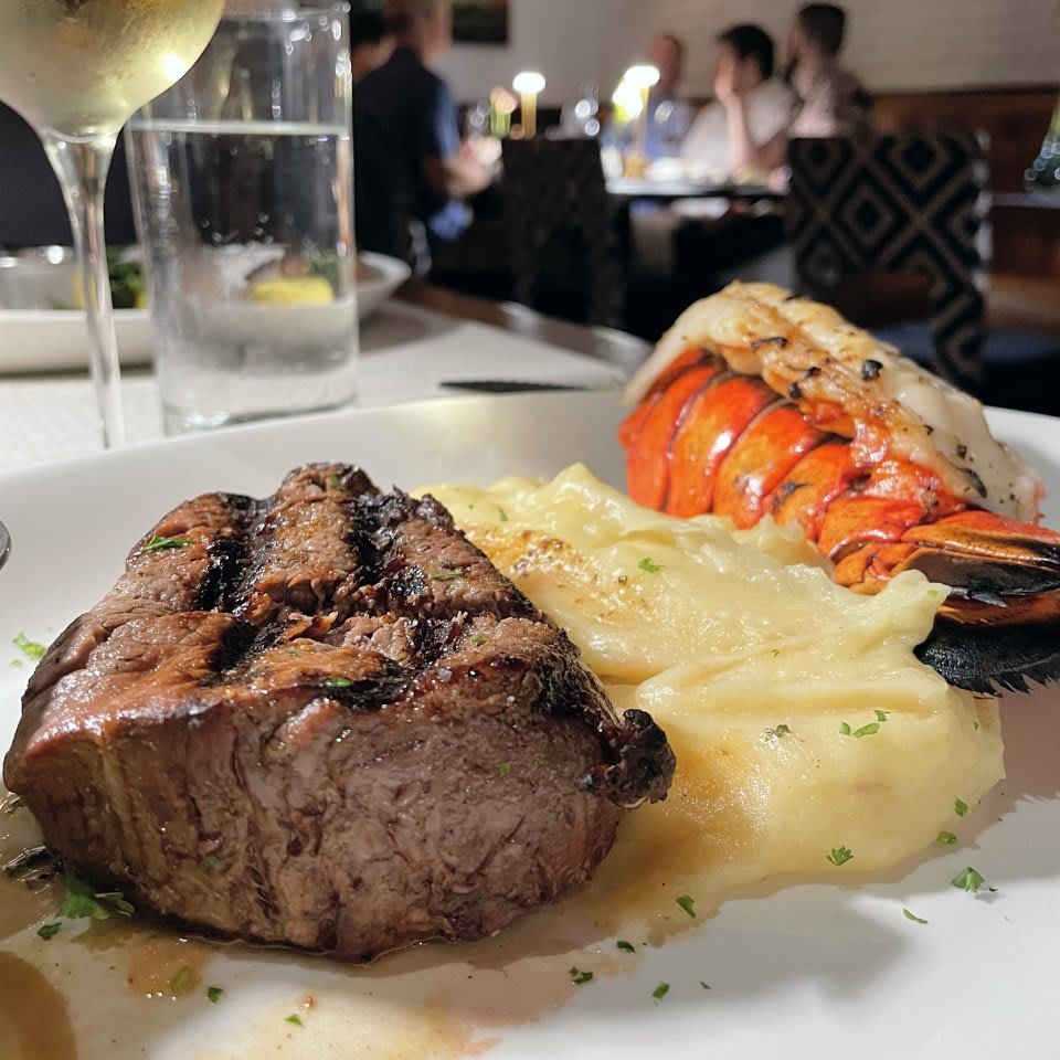A plate with grilled steak, lobster tail, and mashed potatoes in a restaurant setting in Atlanta, Georgia.