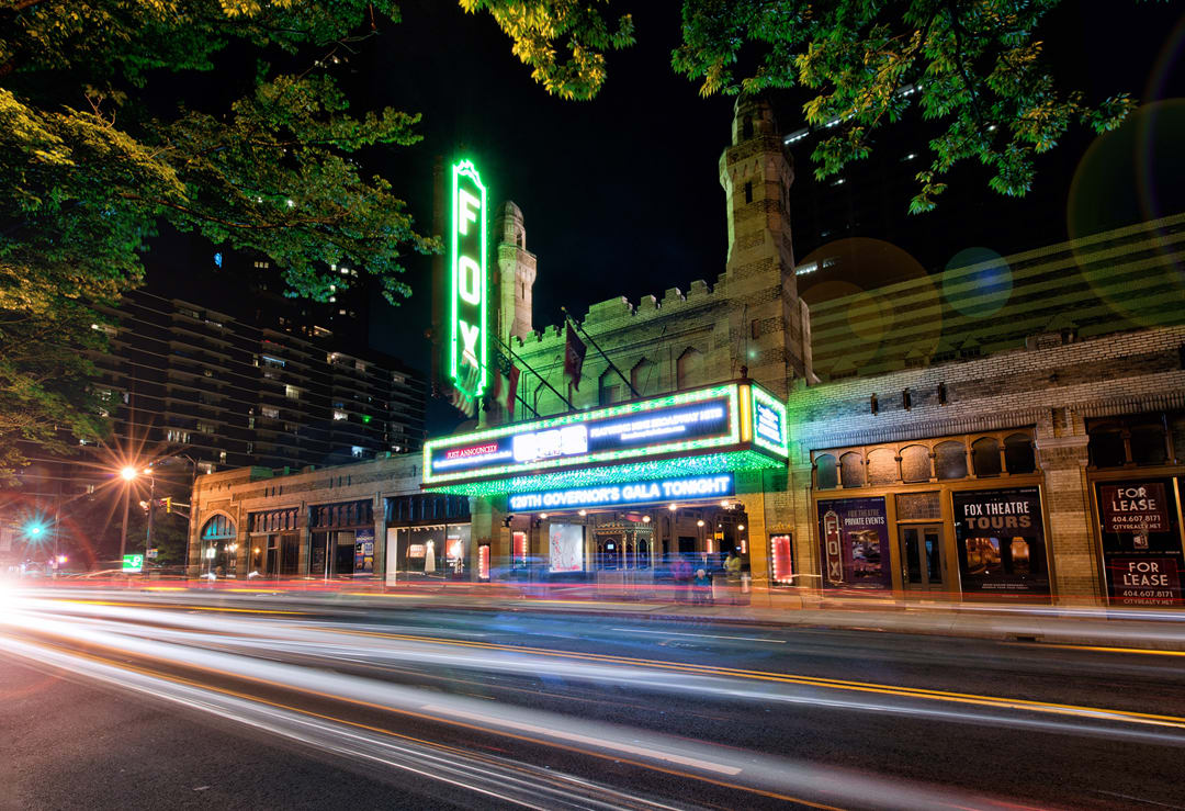A nighttime view of a historic theater with a lit marquee advertising an event in Atlanta, Georgia.