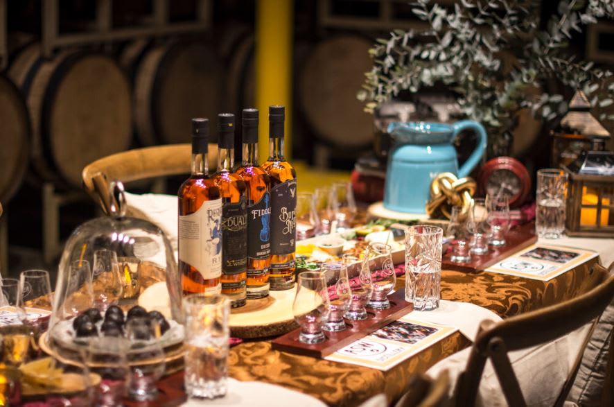 A rustic table set for a whiskey tasting, featuring bottles, glasses, and a variety of snacks in Atlanta, Georgia.