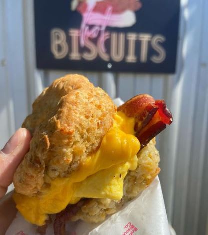 A hand holds a breakfast biscuit sandwich with egg, cheese, and bacon in Atlanta, Georgia.