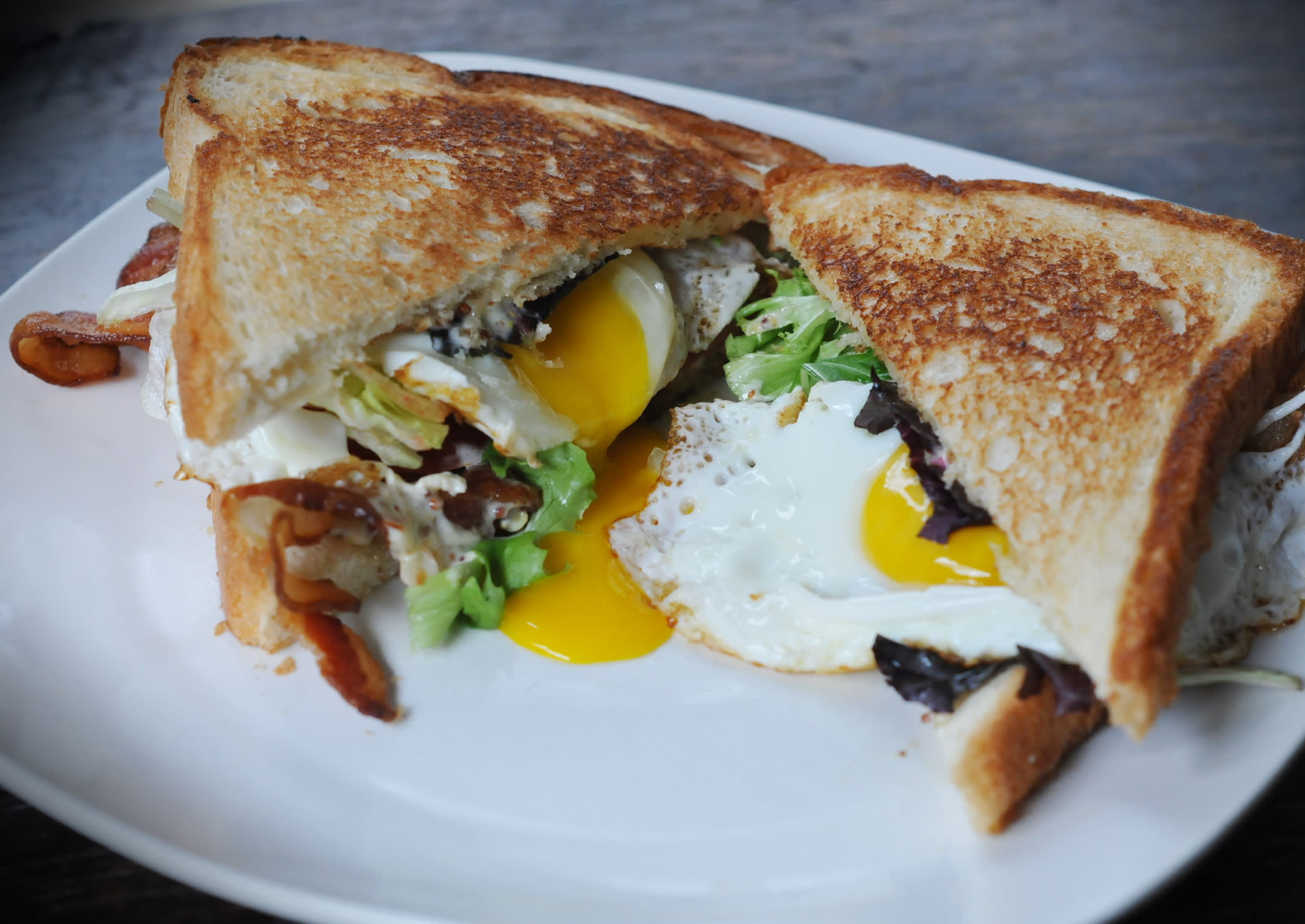 A mouthwatering breakfast sandwich with fried eggs, bacon, and lettuce on toasted bread in Atlanta, Georgia.