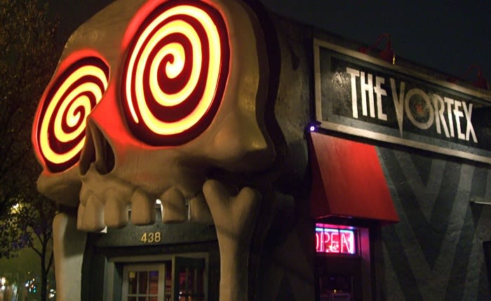 A building with a giant, illuminated skull facade featuring swirling red eyes and a neon 'Open' sign in Atlanta, Georgia.