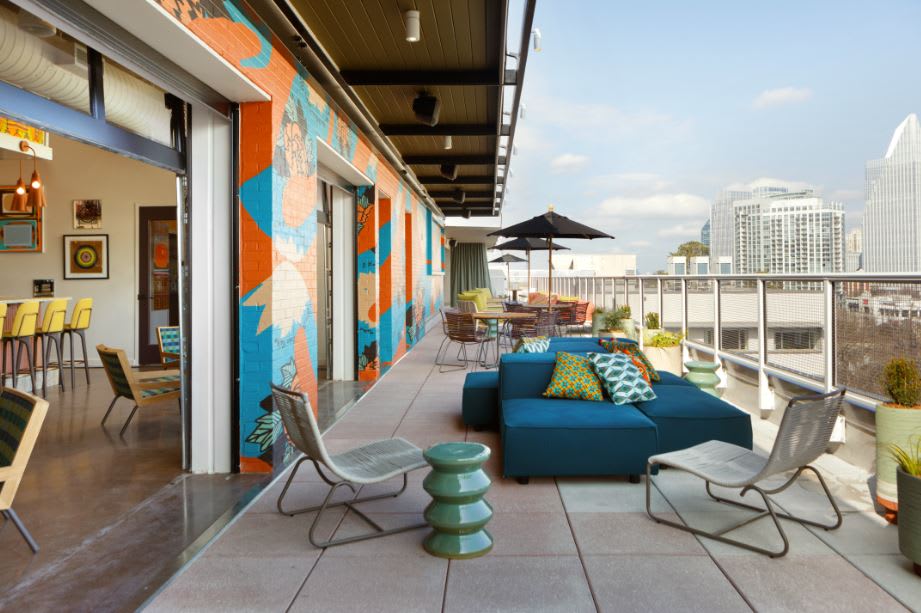 A rooftop patio with colorful furniture and a vibrant mural overlooking a city skyline in Atlanta, Georgia.