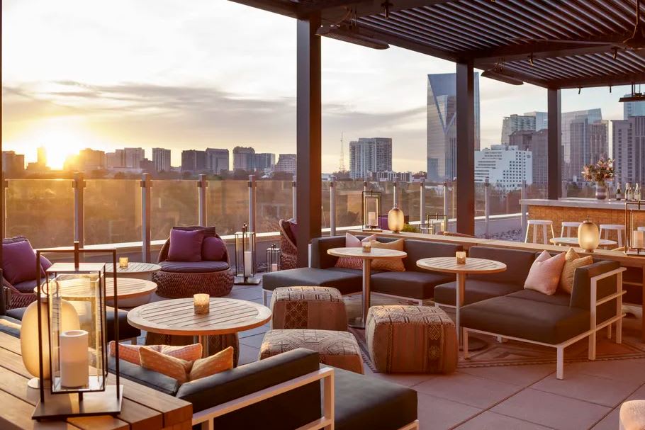 A rooftop patio at sunset with comfortable seating, tables, and a city skyline view in Atlanta, Georgia.