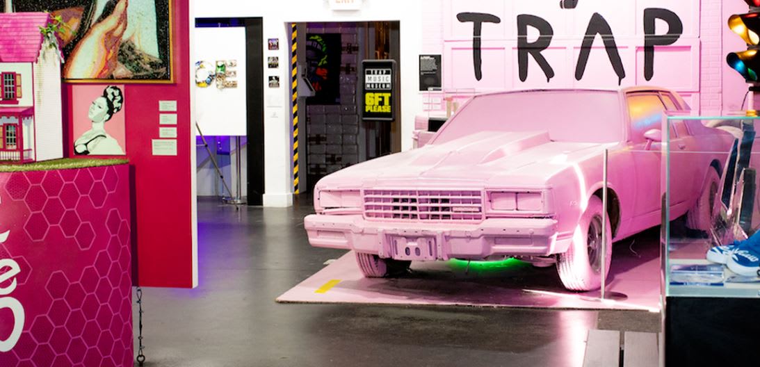 A pink car is displayed in a room with pink walls and a sign reading 'TRAP' in Atlanta, Georgia.