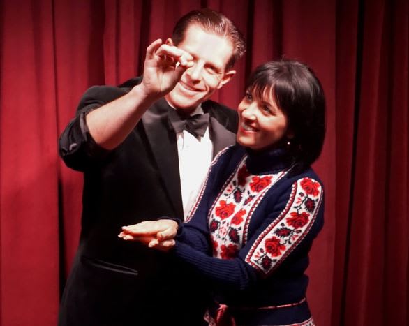 A man in a tuxedo and a woman in a floral sweater dance together on stage in Atlanta, Georgia.
