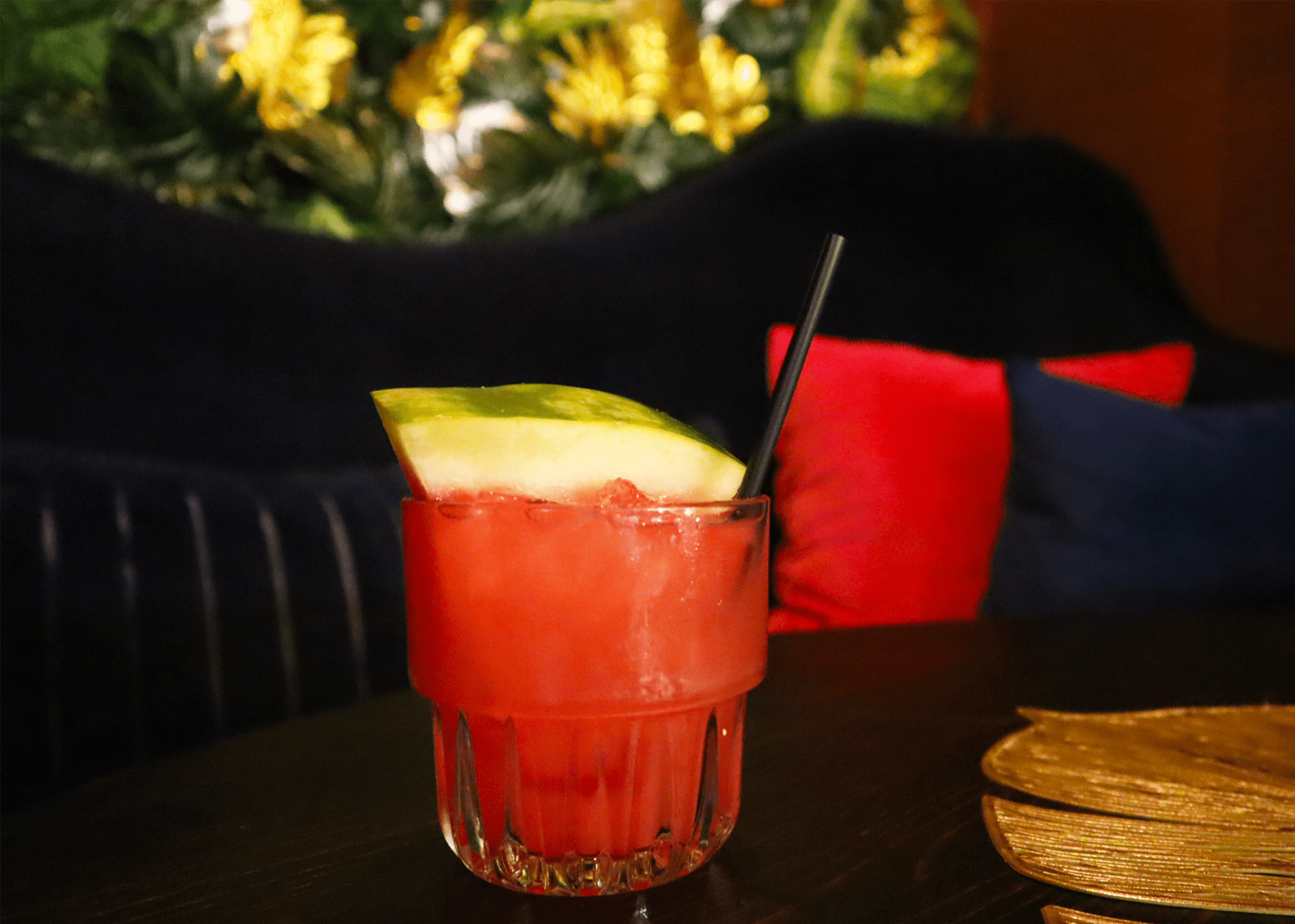 A vibrant red cocktail garnished with a watermelon wedge sits on a dark table in Atlanta, Georgia.