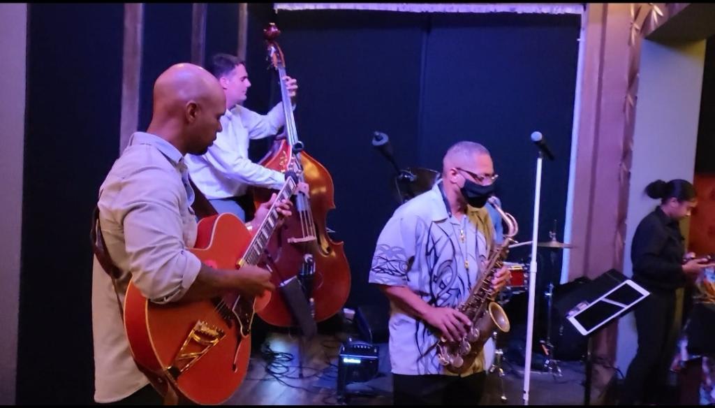 A jazz quartet performs on stage with a saxophonist, guitarist, bassist, and drummer in Atlanta, Georgia.