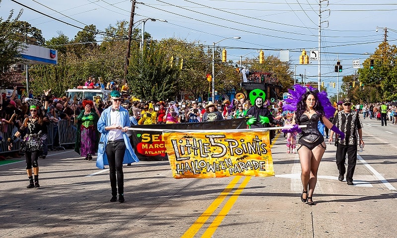 A vibrant Halloween parade featuring costumed participants marching down a city street in Atlanta, Georgia.