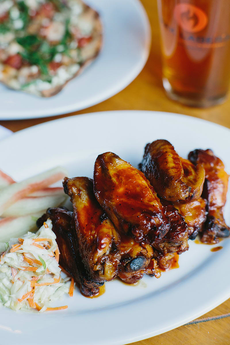 A plate of saucy buffalo chicken wings with coleslaw and celery sticks in Atlanta, Georgia.