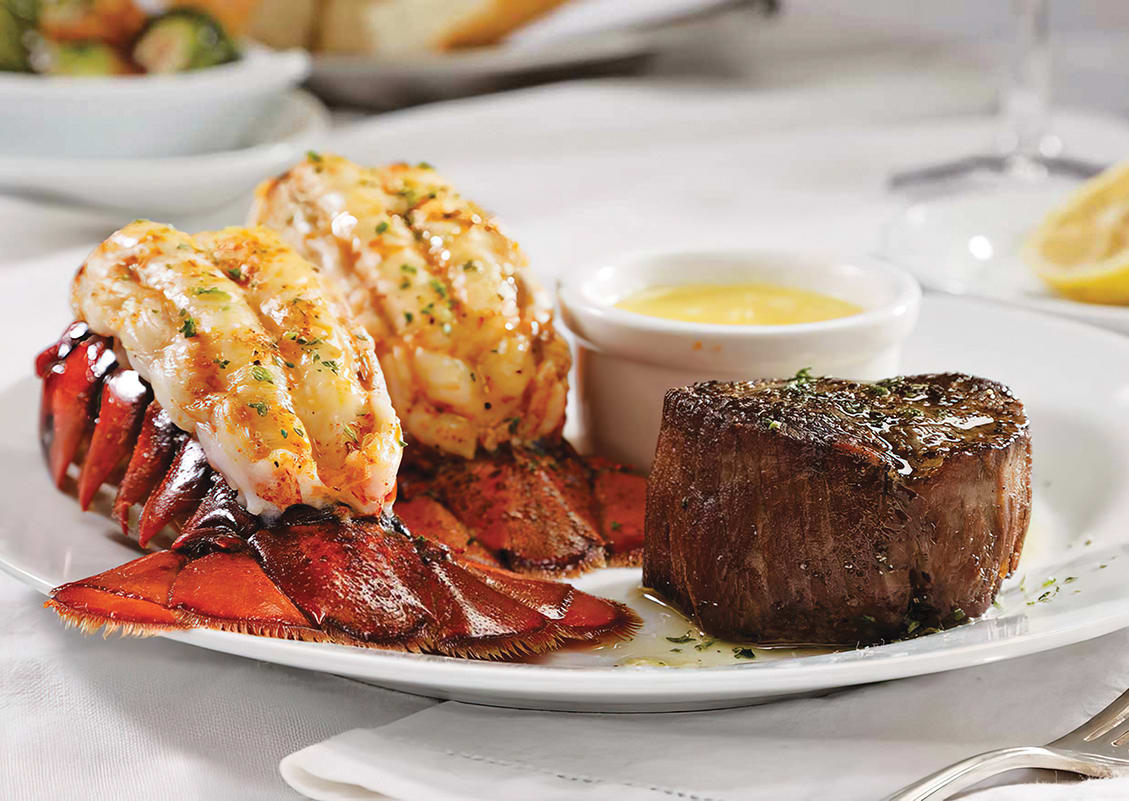 A plate featuring a grilled lobster tail, filet mignon, and a side of sauce in Atlanta, Georgia.