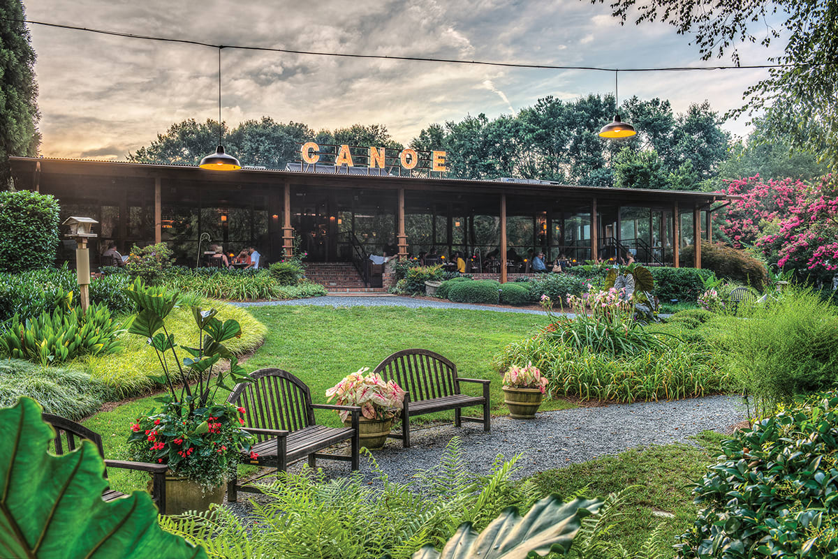 A serene garden with wooden benches, colorful flowers, and a rustic restaurant building in Atlanta, Georgia.