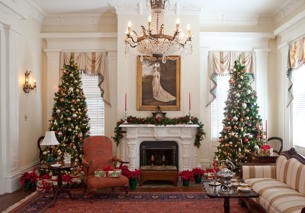 Elegant living room decorated for Christmas with two large trees, fireplace, and vintage furniture in Atlanta, Georgia.