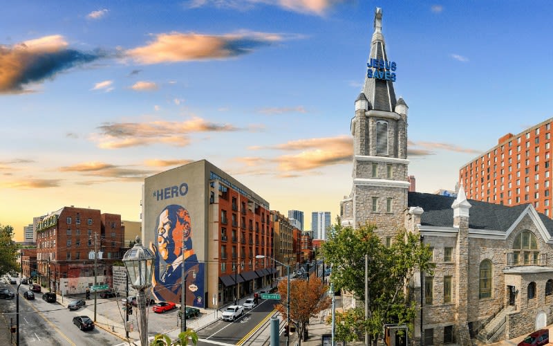 A cityscape at sunset with a prominent mural and a church spire in Atlanta, Georgia.