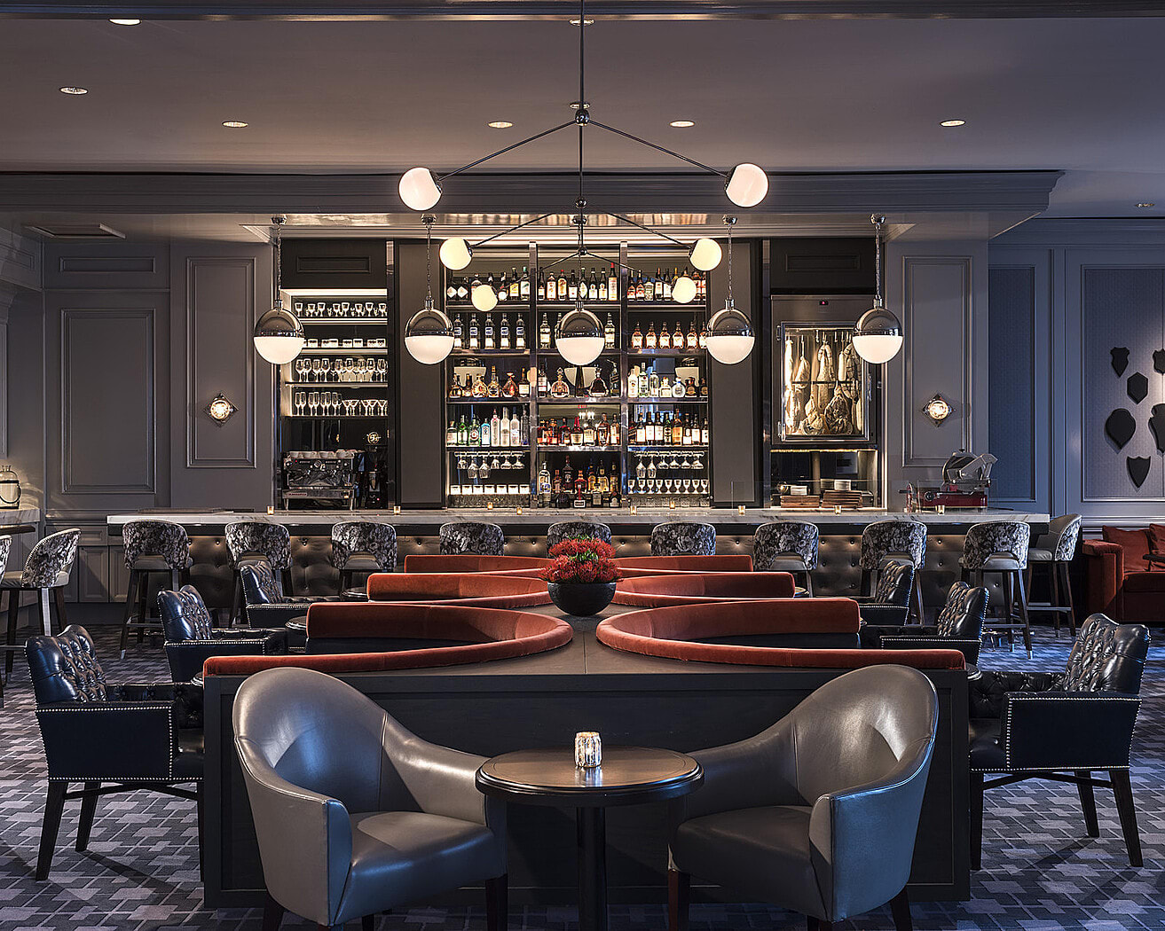 Elegant, modern bar with circular red seating, leather chairs, and a sophisticated chandelier in Atlanta, Georgia.