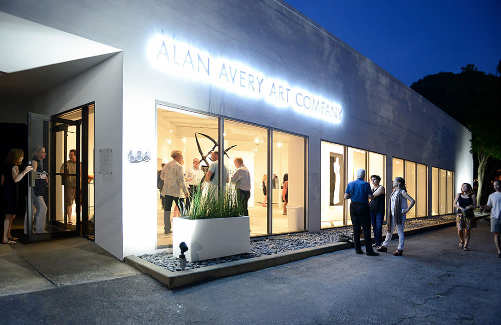 People gather outside a modern art gallery with illuminated signage and large windows in Atlanta, Georgia.