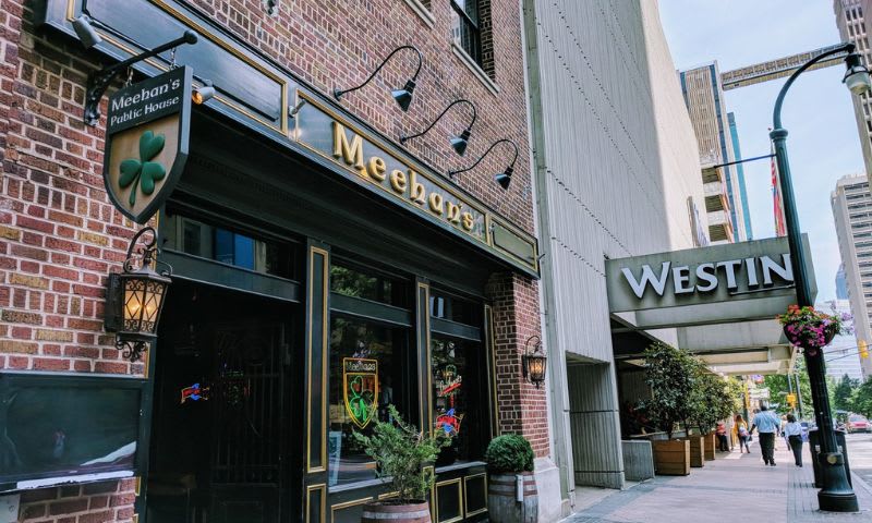 A brick building with a green shamrock sign above the entrance to Meehan's Public House in Atlanta, Georgia.