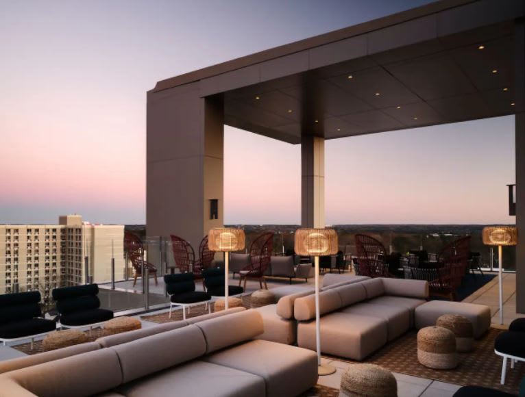 A rooftop lounge with modern furniture and string lights overlooking a cityscape at dusk in Atlanta, Georgia.