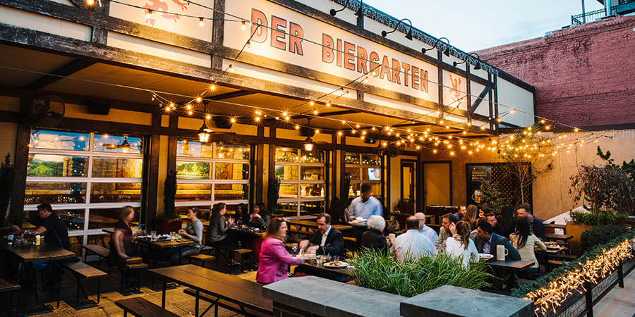 Outdoor beer garden with string lights, wooden tables, and people dining at night in Atlanta, Georgia.