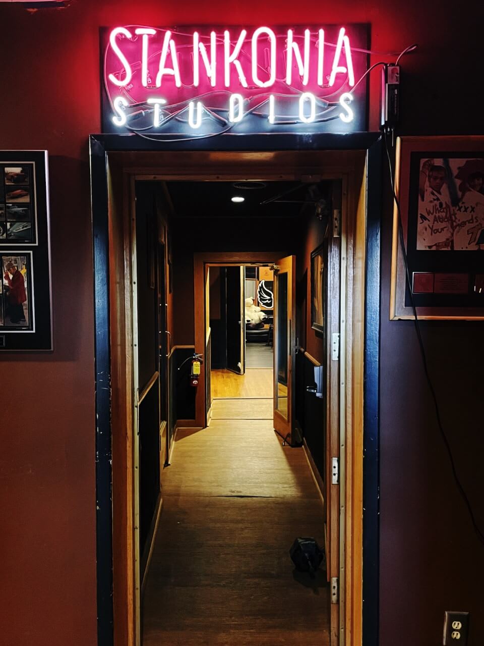 A dimly lit hallway leads to a studio with a red neon sign reading 'STANKONIA STUDIOS' above the door in Atlanta, Georgia.