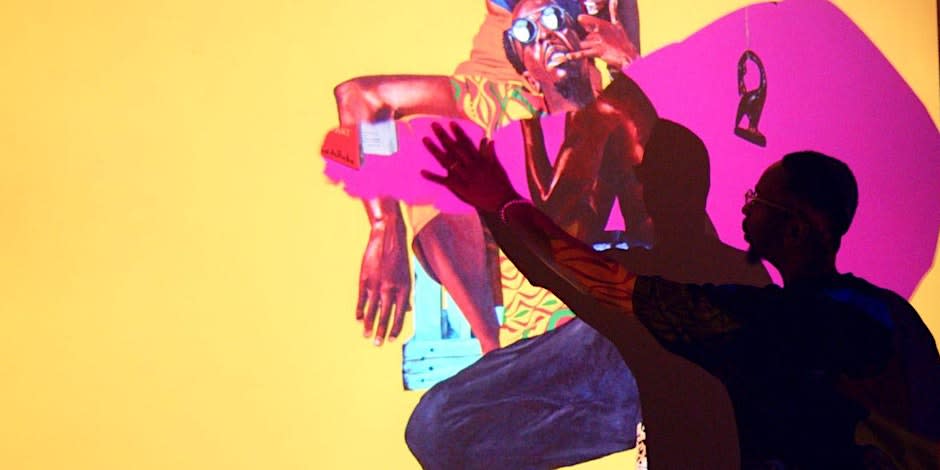 A man's shadow interacts with a vibrant, abstract painting of a colorful figure in Atlanta, Georgia.