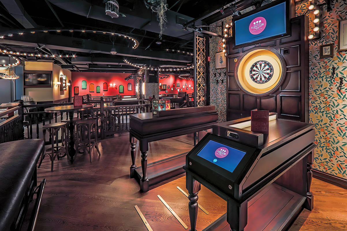 A dimly lit, vintage-style bar with red walls, wooden tables, and a dartboard mounted on a wall in Atlanta, Georgia.