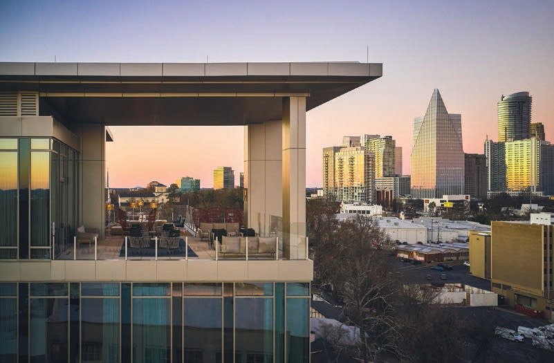Modern high-rise building with expansive glass windows overlooking a city skyline at sunset in Atlanta, Georgia.