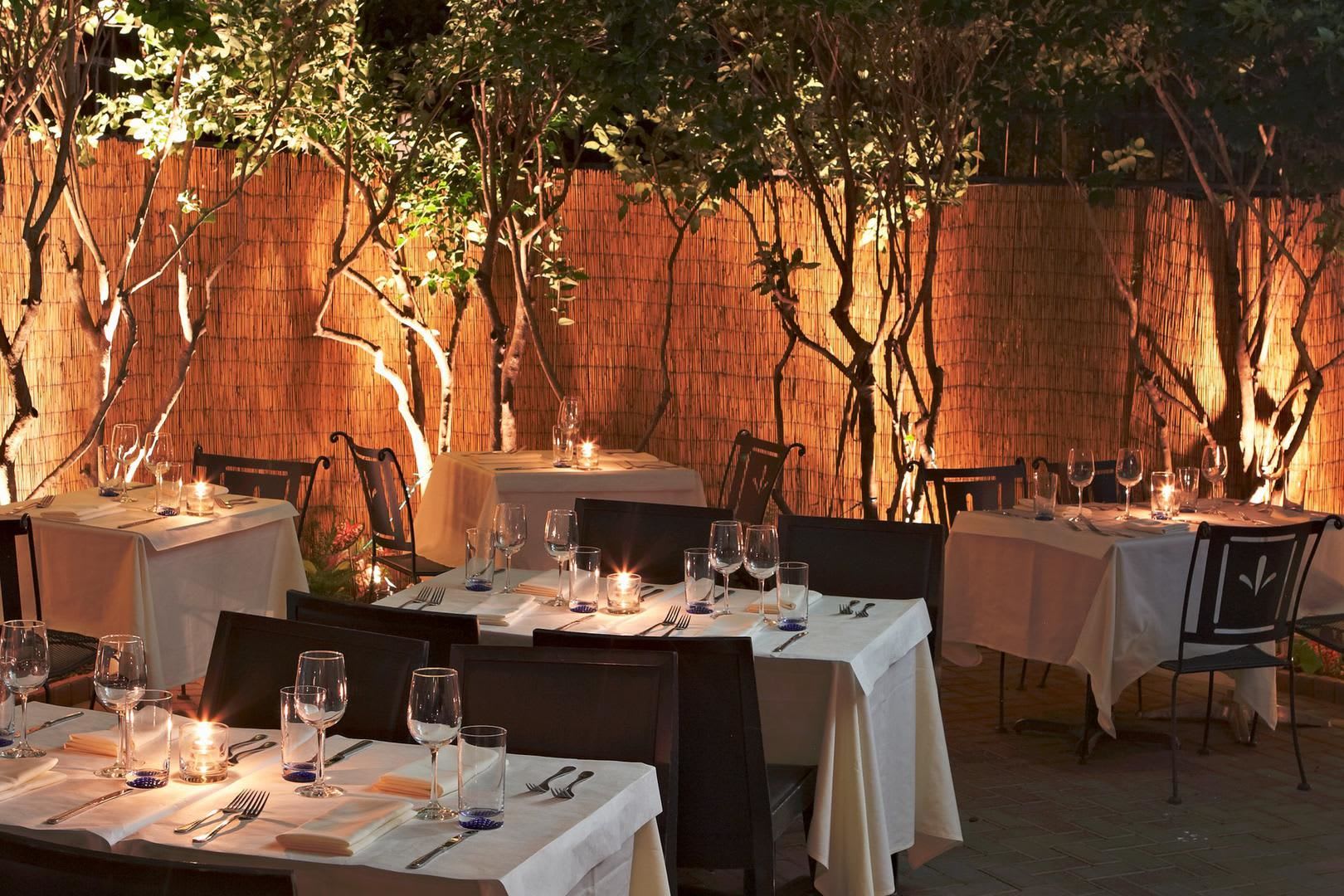 Outdoor restaurant patio with candlelit tables and chairs under trees at night in Atlanta, Georgia.