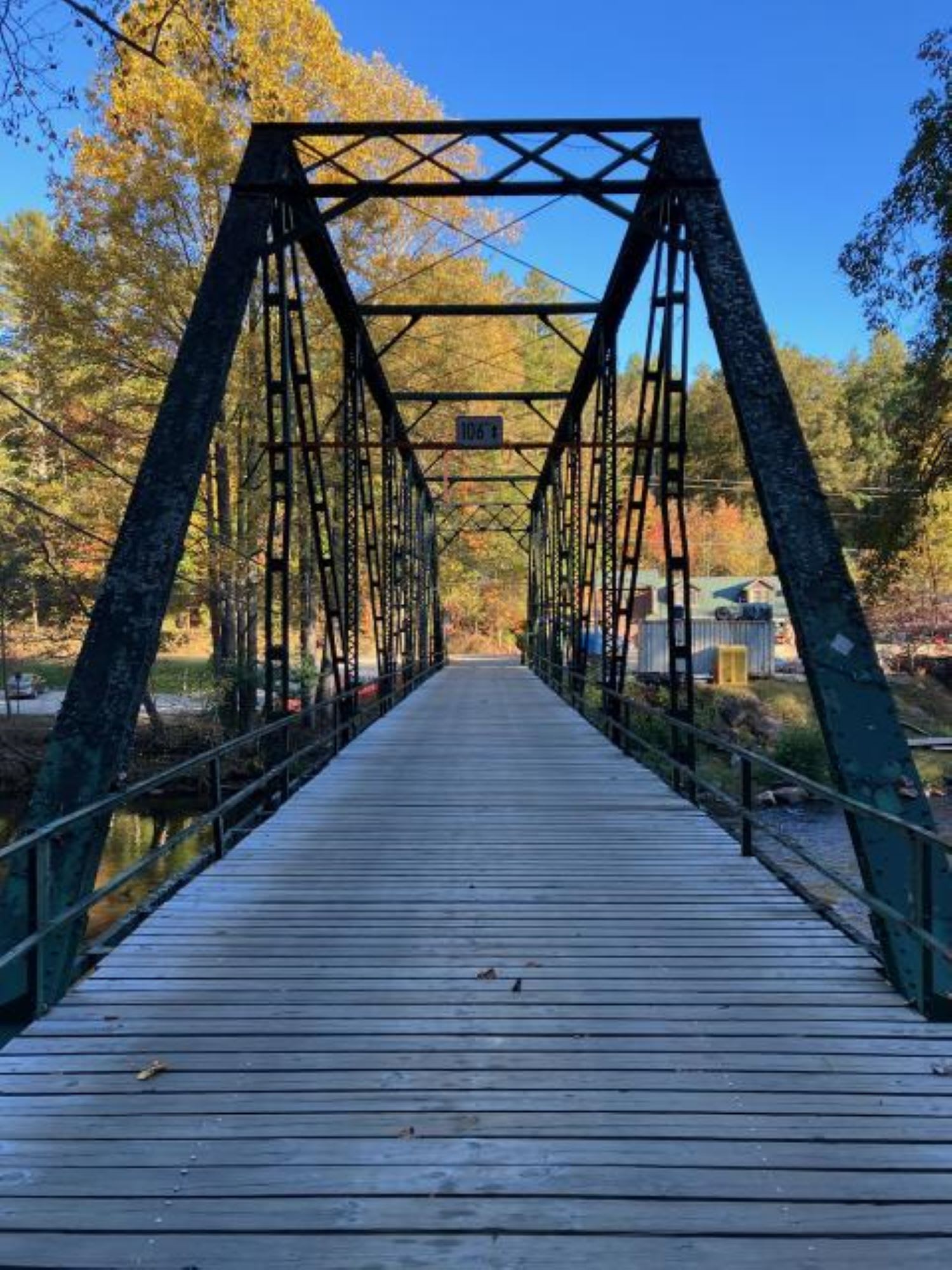 A wooden bridge with metal trusses spans a river, surrounded by autumn trees in Atlanta, Georgia.