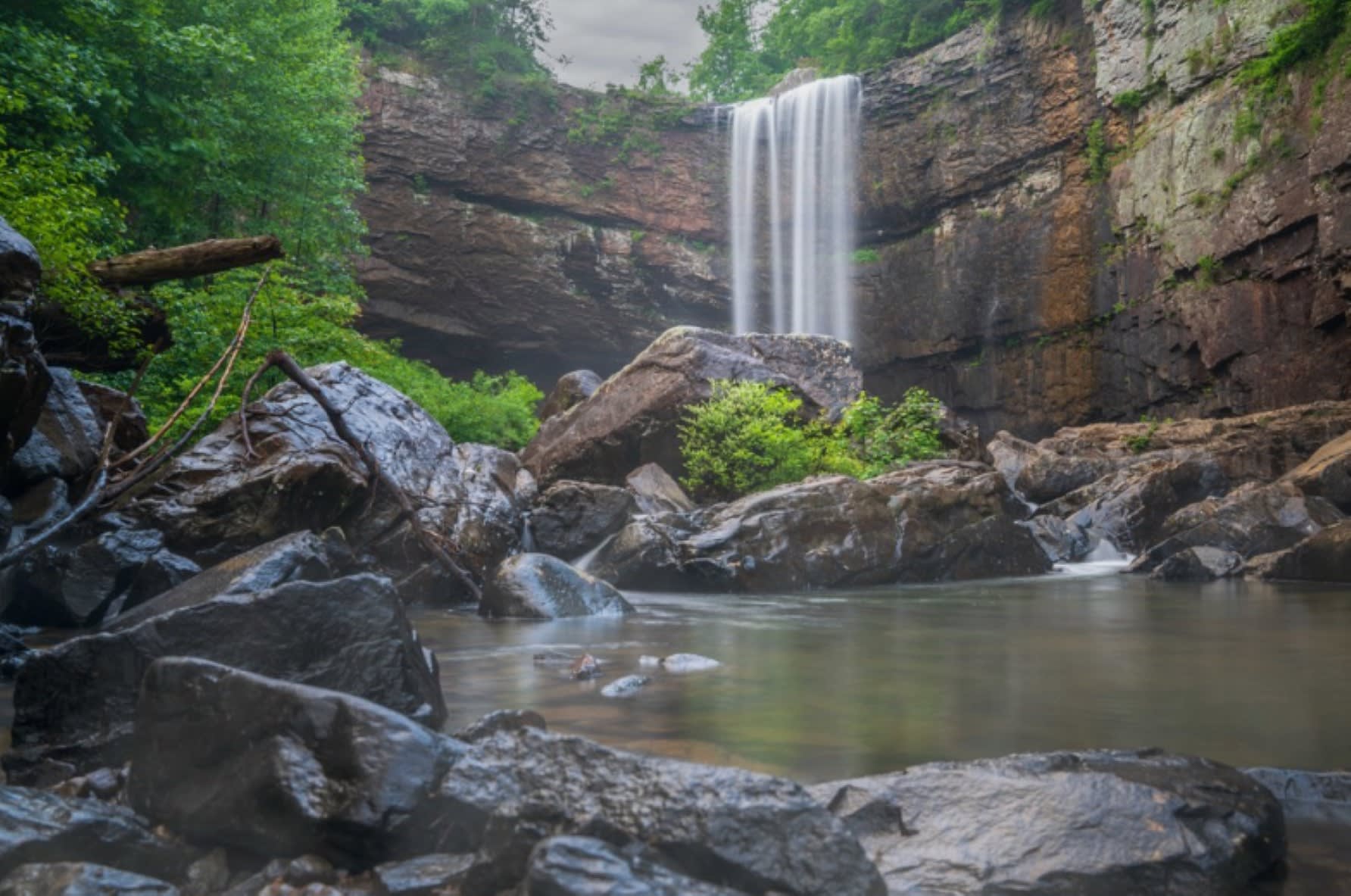 A majestic waterfall cascades down a rocky cliff, surrounded by lush green foliage in Atlanta, Georgia.