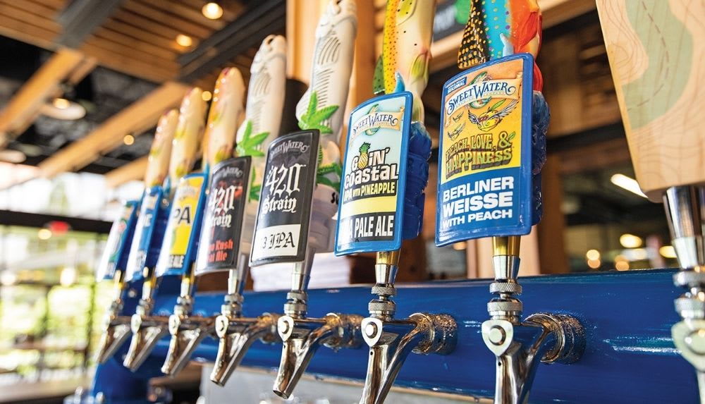 A row of colorful beer taps with unique labels and fish-shaped handles at a bar in Atlanta, Georgia.