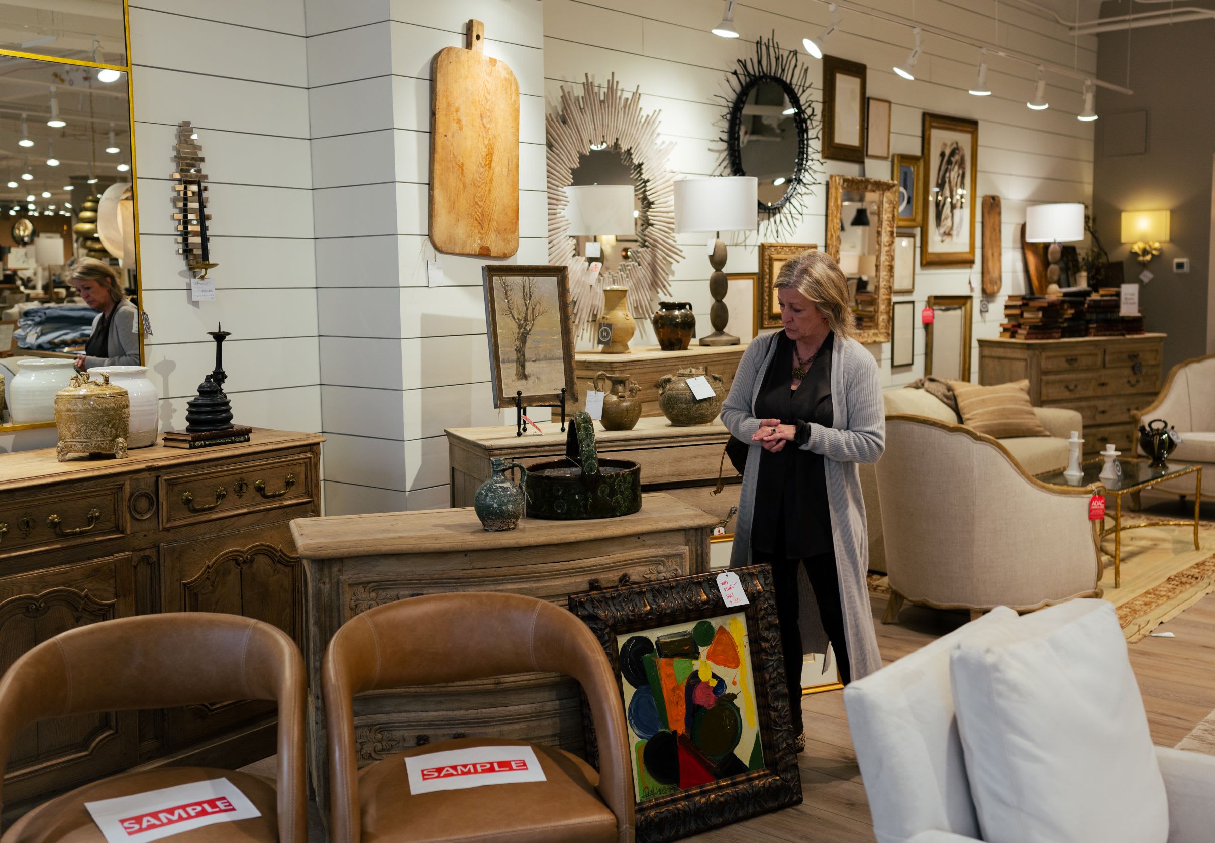 A woman examines framed art and decorative items in a well-lit furniture showroom in Atlanta, Georgia.