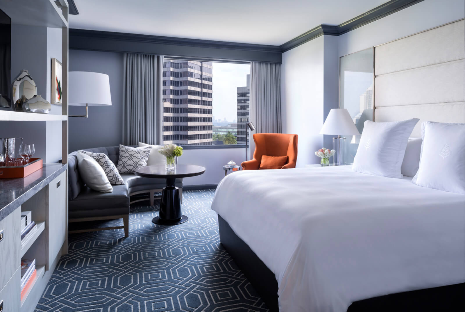A modern hotel room with a king bed, sitting area, and city view window in Atlanta, Georgia.
