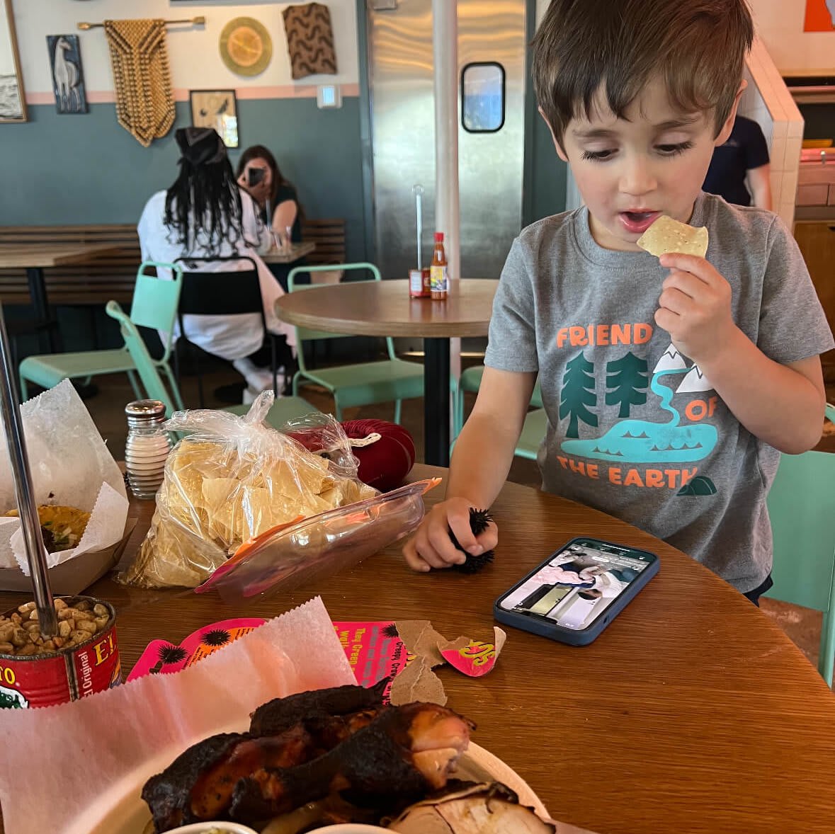A young boy enjoys a tortilla chip at a restaurant table with food and condiments in Atlanta, Georgia.