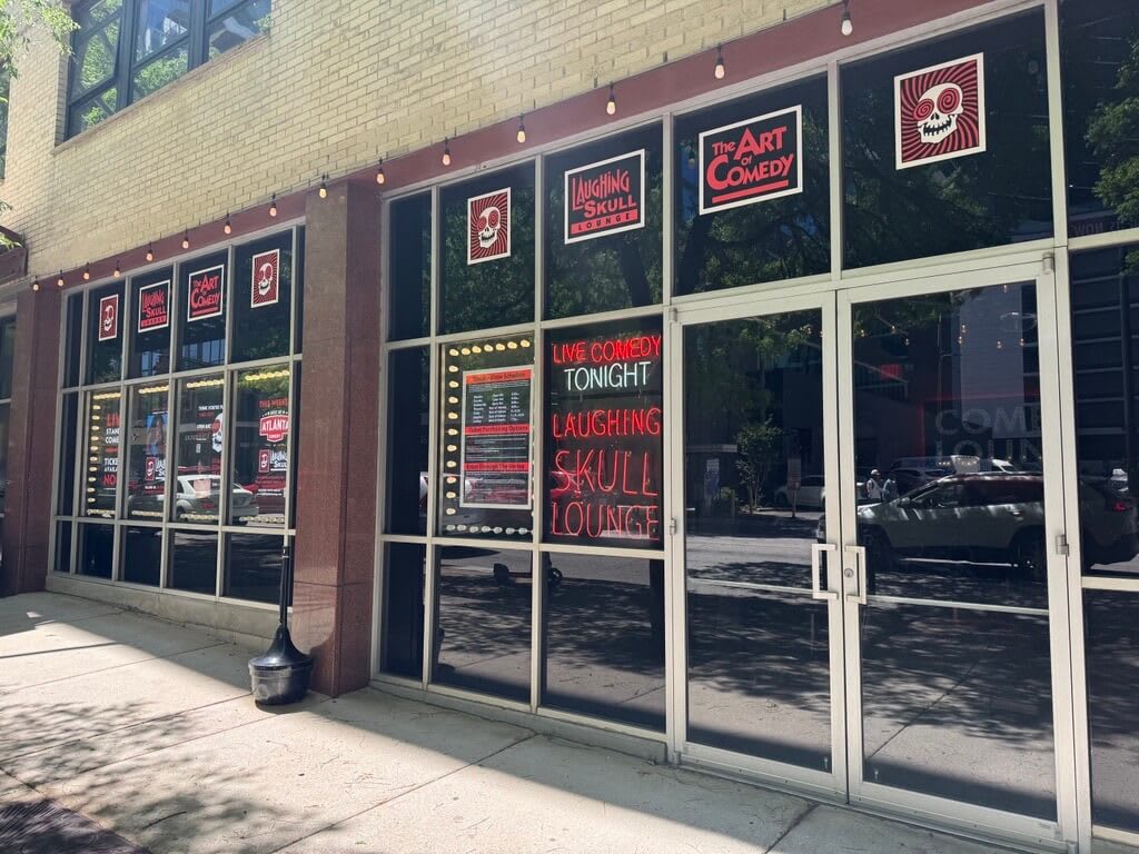A comedy club with a skull logo and neon signs advertising live comedy tonight in Atlanta, Georgia.