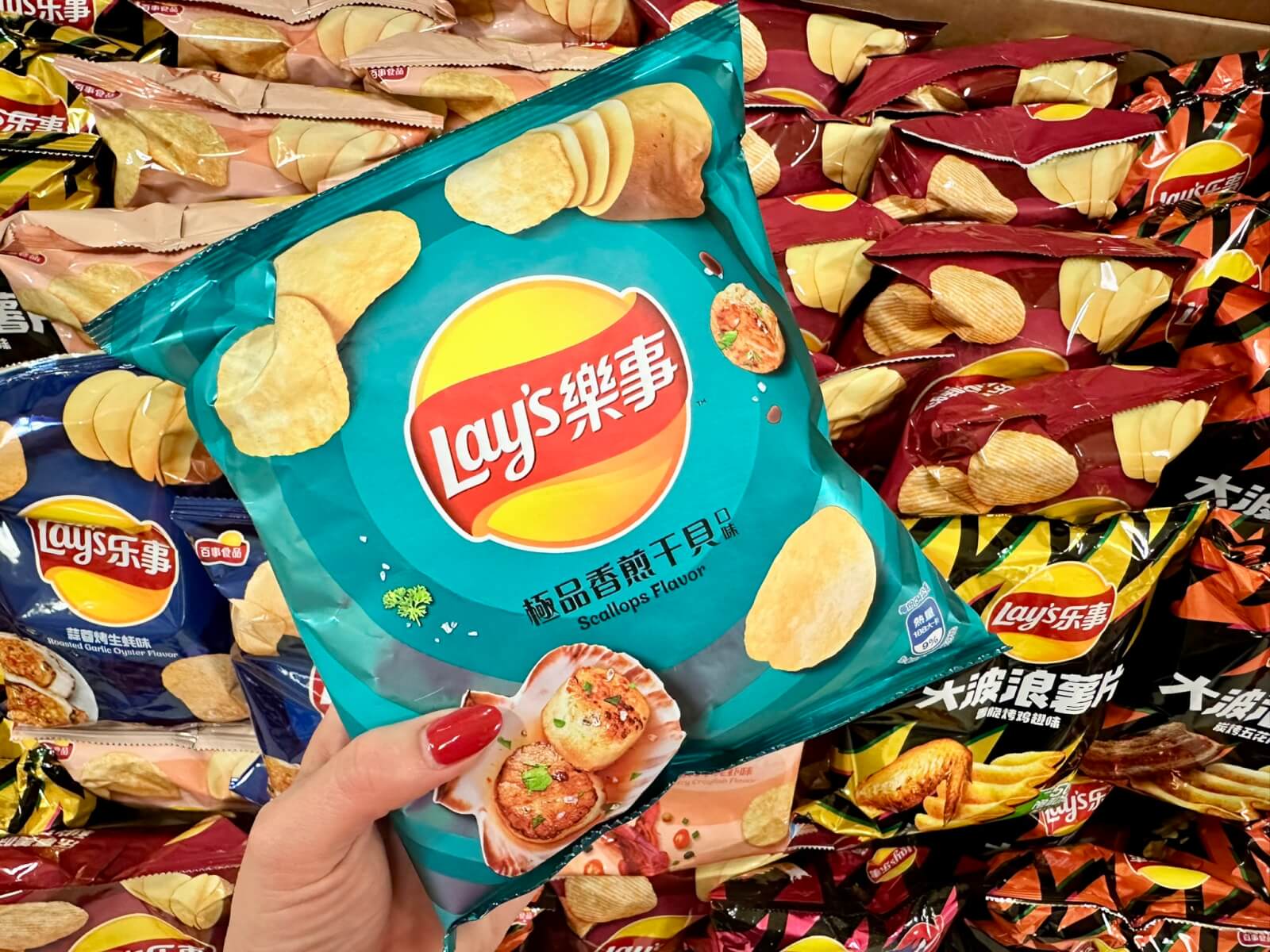 A hand holds a bag of scallop-flavored Lay's chips among other Lay's varieties in Atlanta, Georgia.