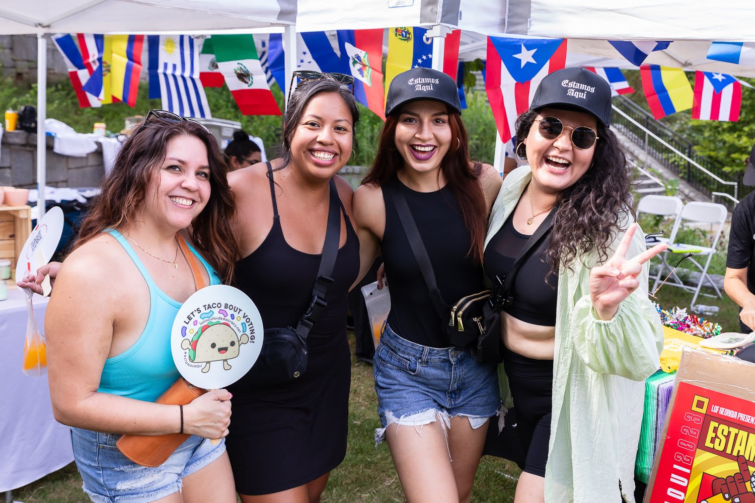 Four women in matching black outfits and caps pose together at a colorful outdoor event in Atlanta, Georgia.