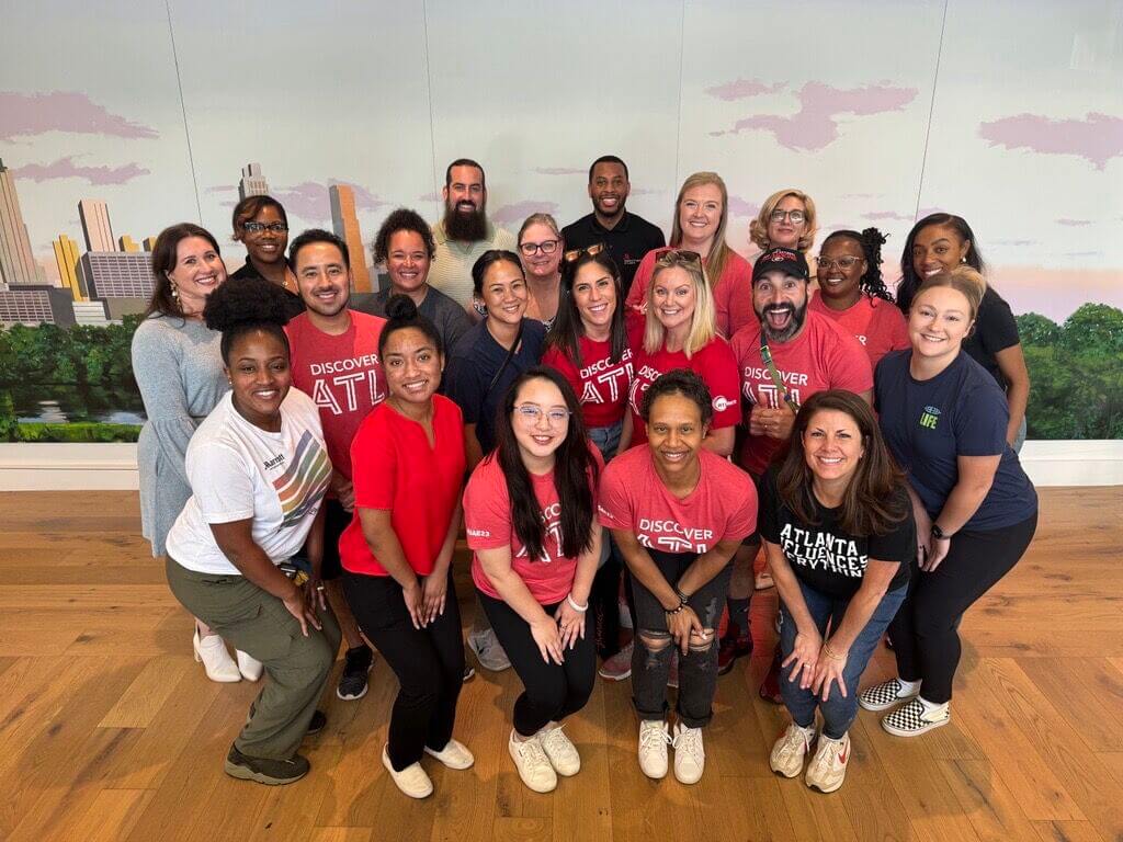 A diverse group of people wearing red shirts with 'Discover ATL' pose together indoors in Atlanta, Georgia.