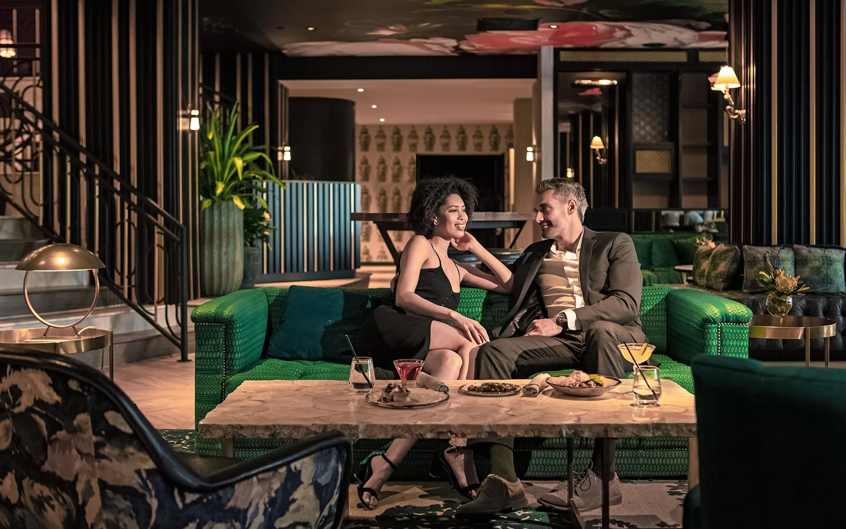 A couple enjoys a romantic evening on a green couch in a stylish, dimly lit lounge in Atlanta, Georgia.