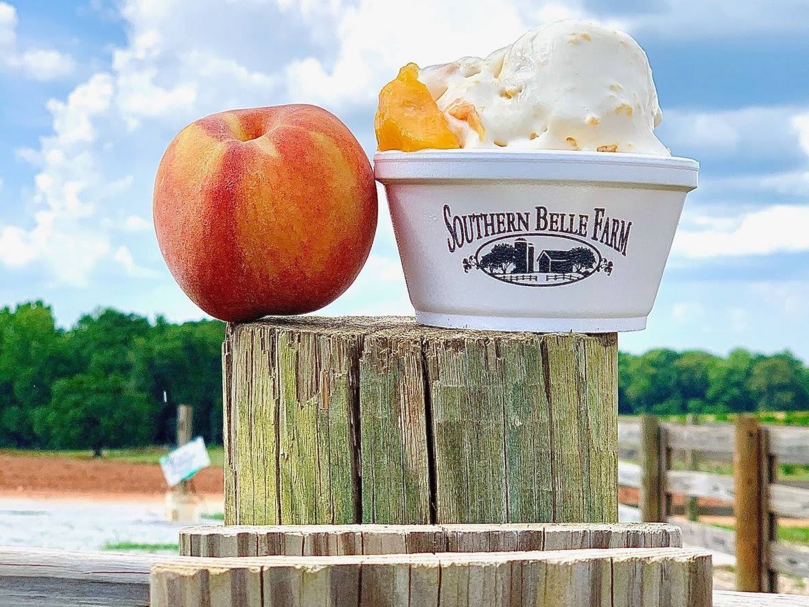A peach sits beside a cup of peach ice cream from Southern Belle Farm in Atlanta, Georgia.