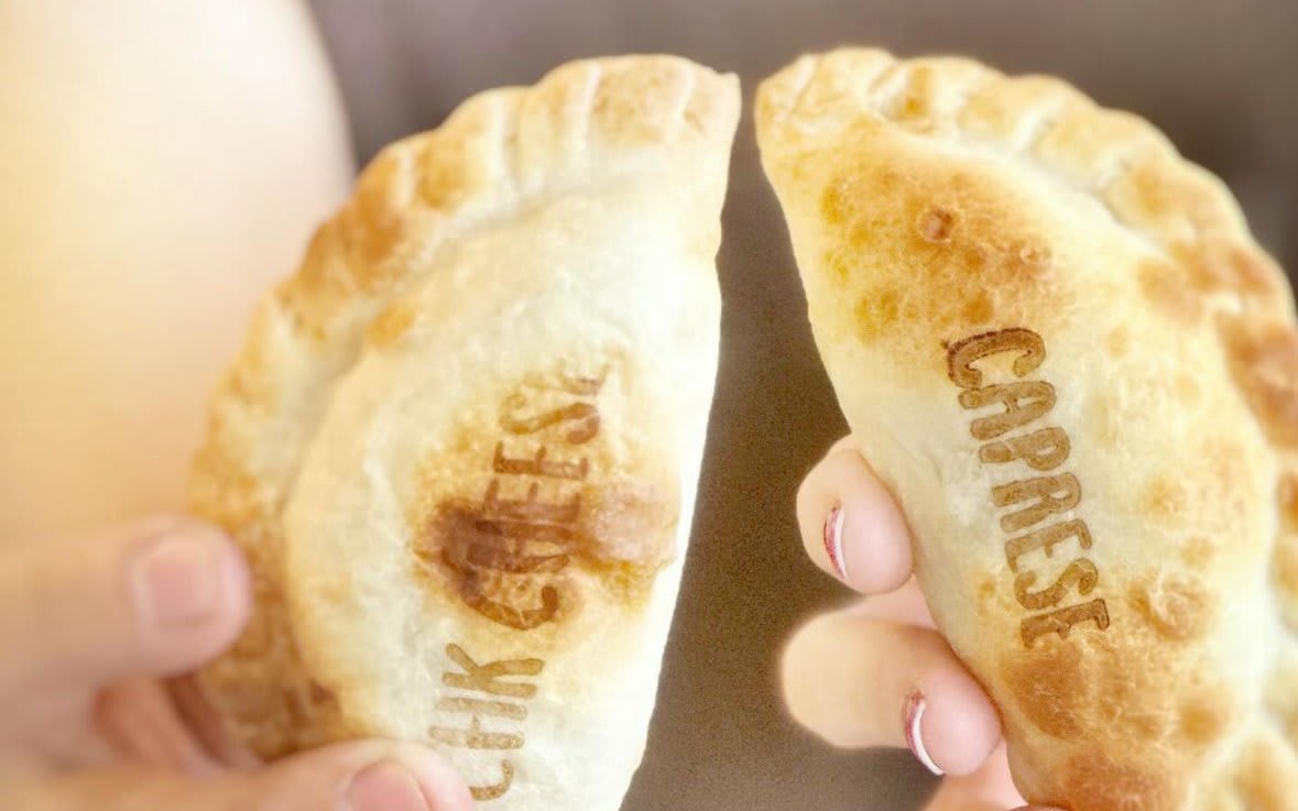 Two golden-brown empanadas with 'Chik Cheese' and 'Caprese' imprinted on them in Atlanta, Georgia.